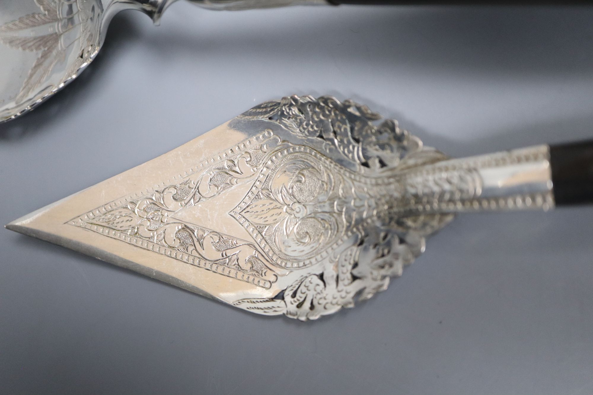 A group of assorted Thai ebony handled engraved white metal servers, one a.f.